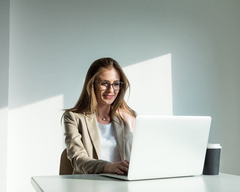 A business woman in glasses focused on her laptop screen